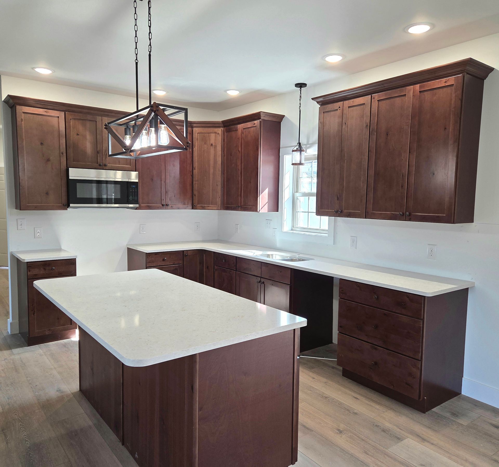 Modern kitchen with dark wood cabinets, white countertops, island, and stainless steel appliances