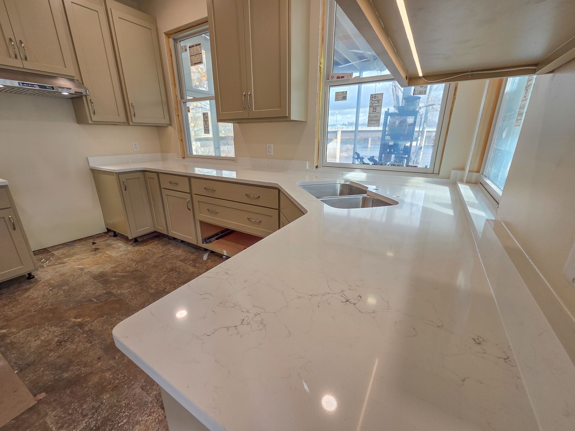 Bright kitchen with beige cabinets, white countertops, and large windows overlooking a city view