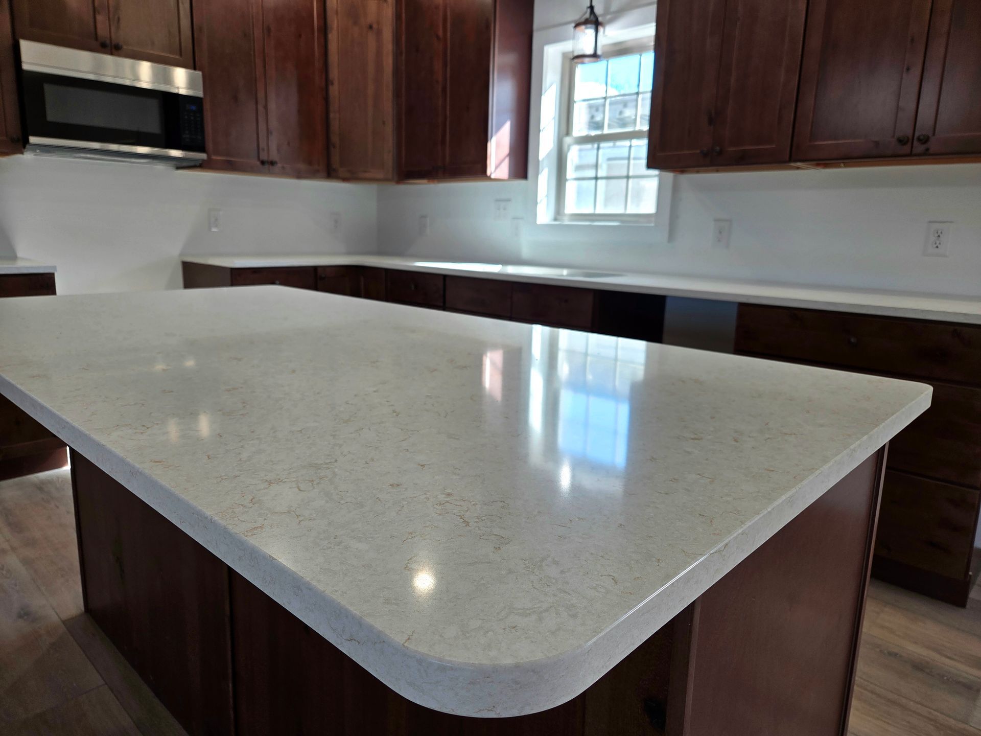 Modern kitchen with a large white quartz island and dark wood cabinets￼