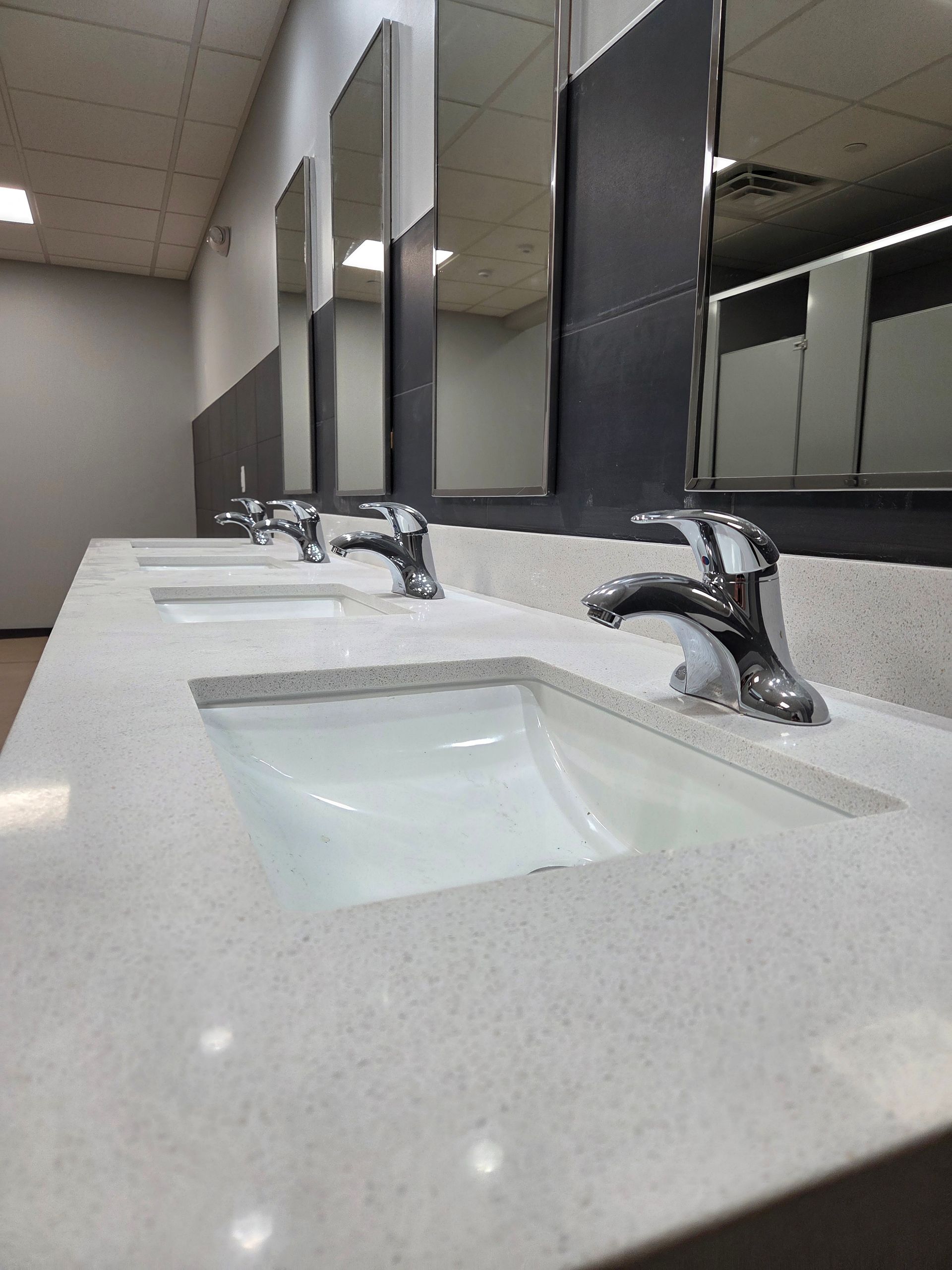 Modern restroom sink with chrome faucets and mirrors, viewed from a low angle.
