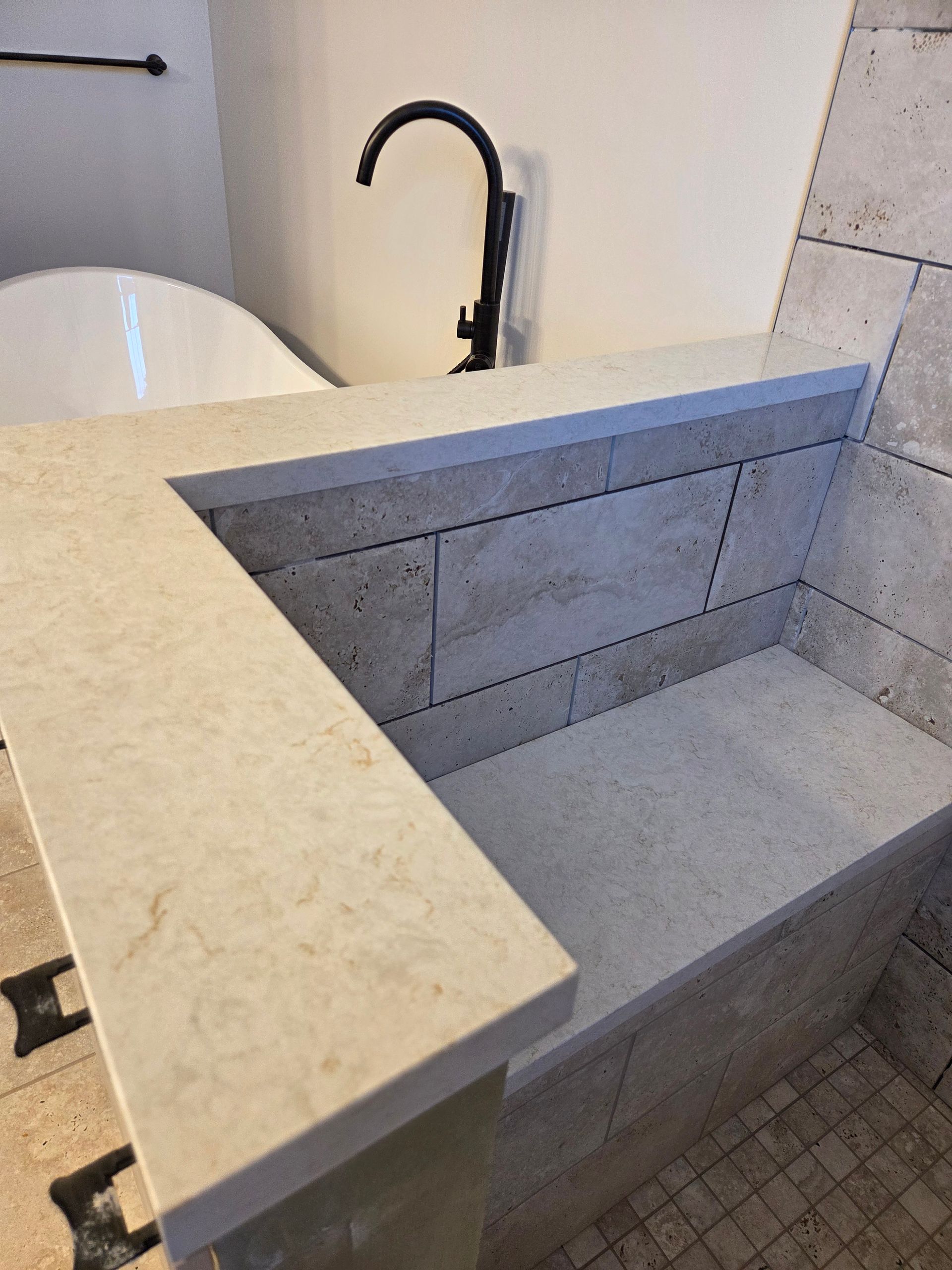 Accessible stone sink with wall-mounted black faucet in a modern bathroom.