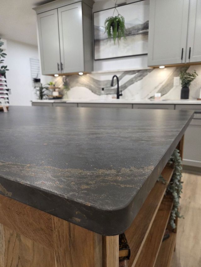 Dark granite kitchen island with rounded edge in a modern, bright kitchen.