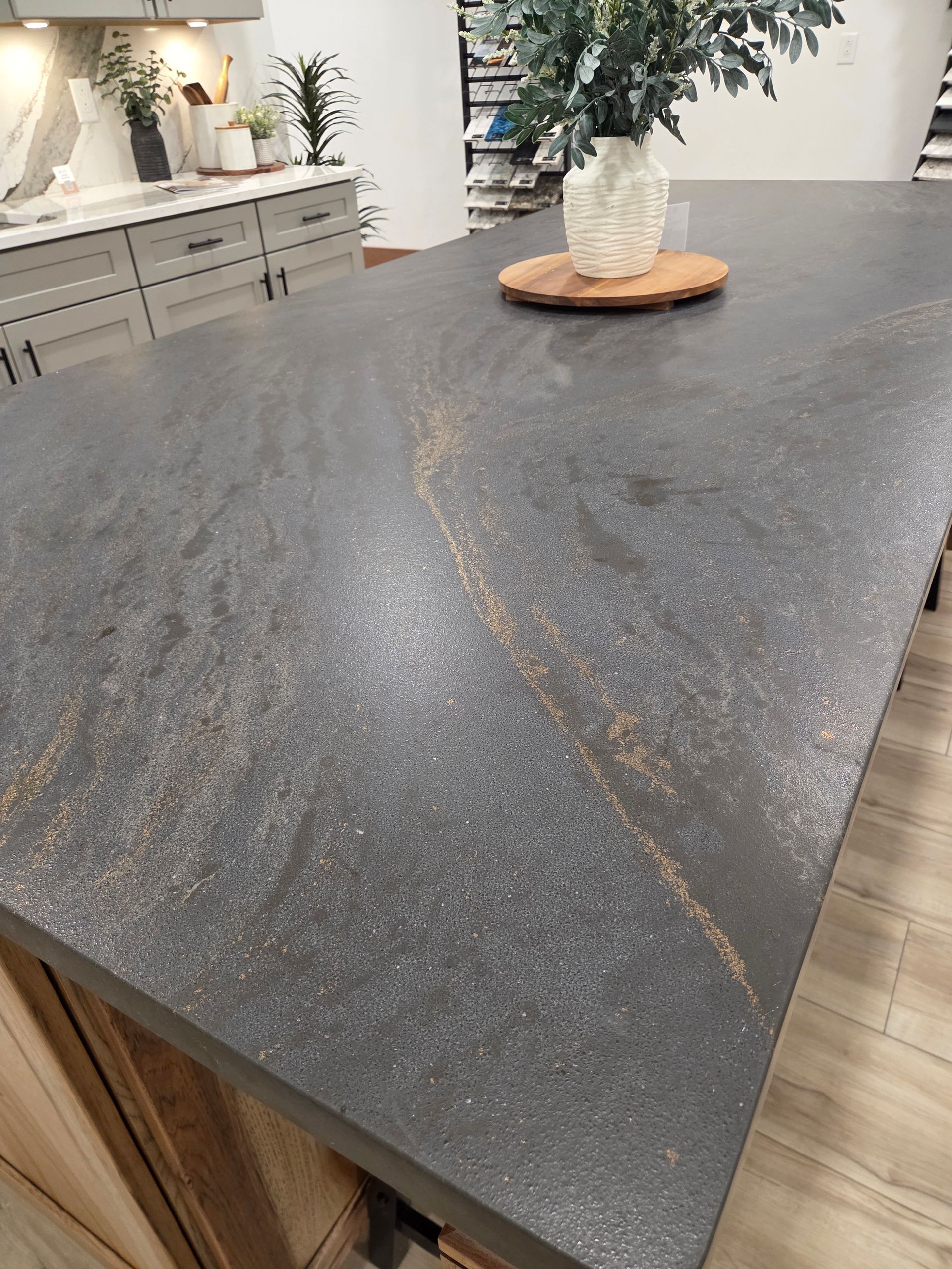 Dark gray stone kitchen island countertop with subtle gold veining and a vase centerpiece