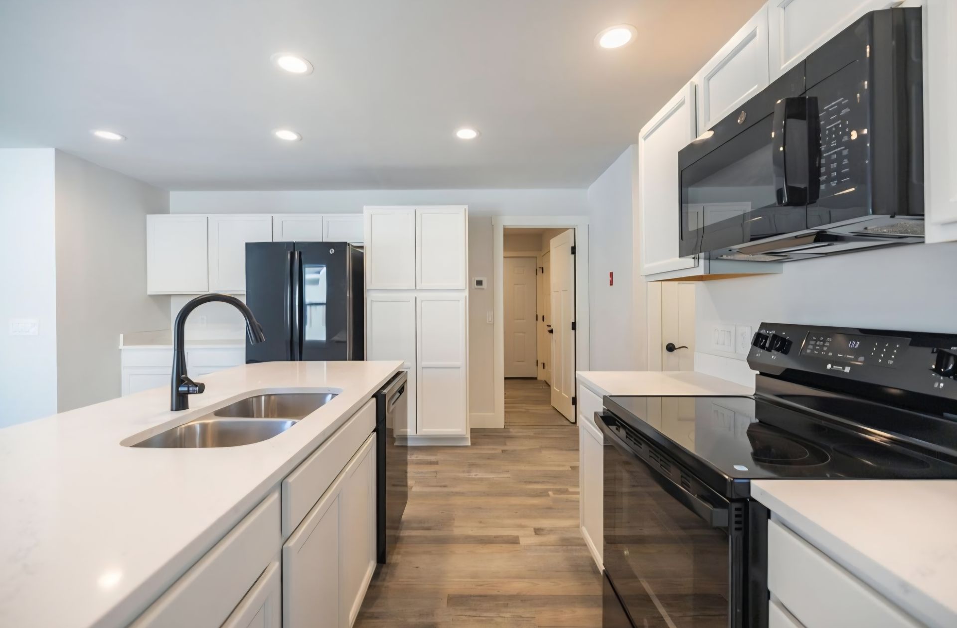 Bright modern white kitchen with island, black appliances, and light wood floors