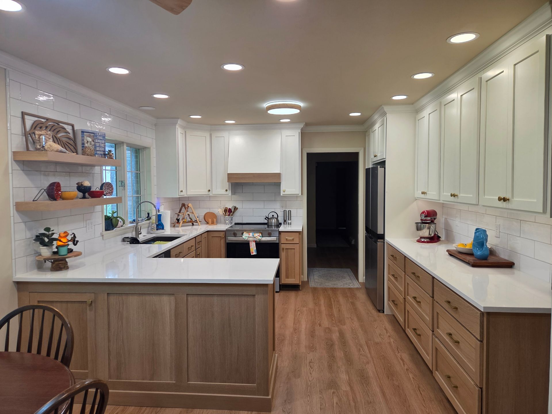 Bright white kitchen with wood floors, long island, and white cabinets, viewed from the dining area.