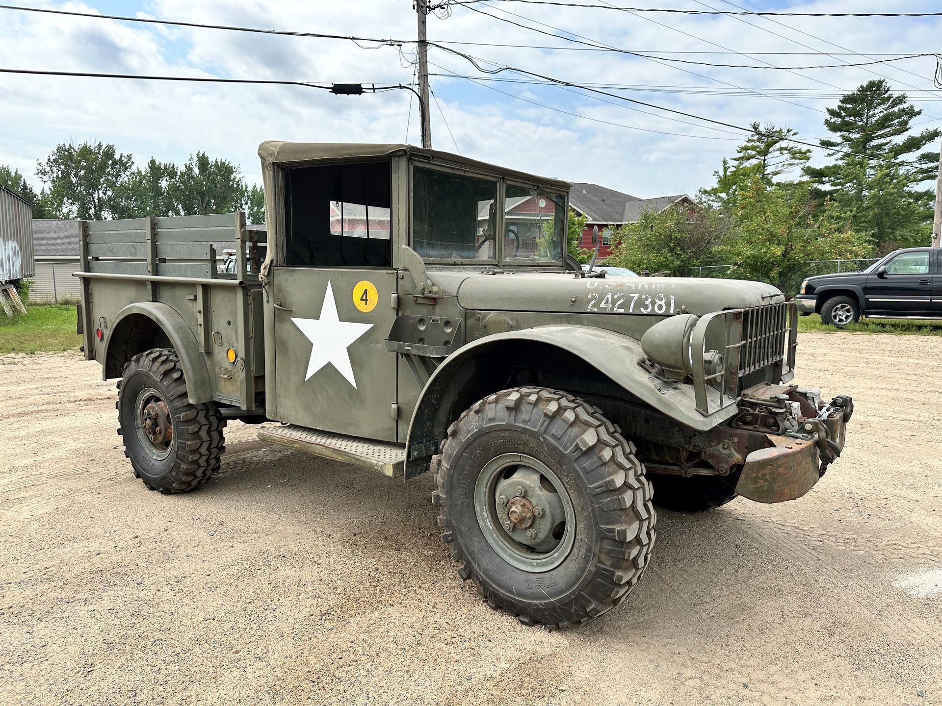 a military truck with a star painted on the side is parked in a gravel lot .