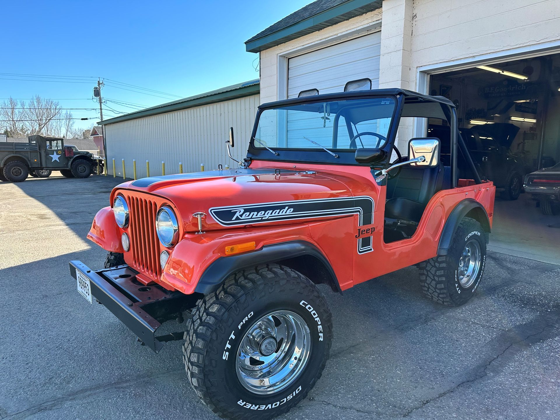 a red jeep is parked in front of a garage .