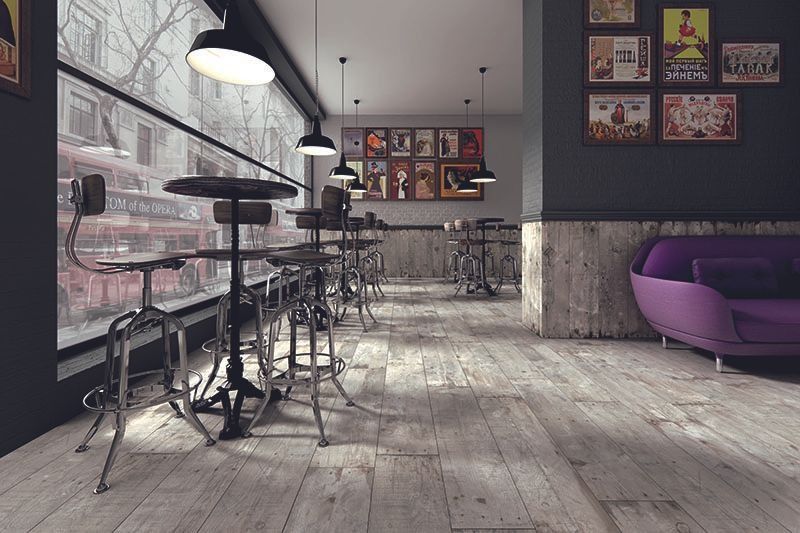 Modern cafe interior with tall stools, hanging lights, wood floors, and a purple sofa