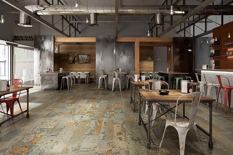 Industrial-style café with wooden tables, metal chairs, and a rustic patterned floor.
