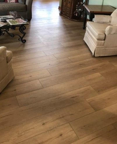 Wood-look flooring in a living room with a cream armchair and dark side tables.