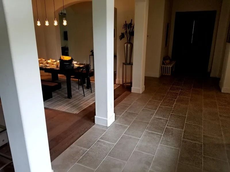 Hallway with tiled floor leading to a dining area with a lit candle and hanging pendant lights