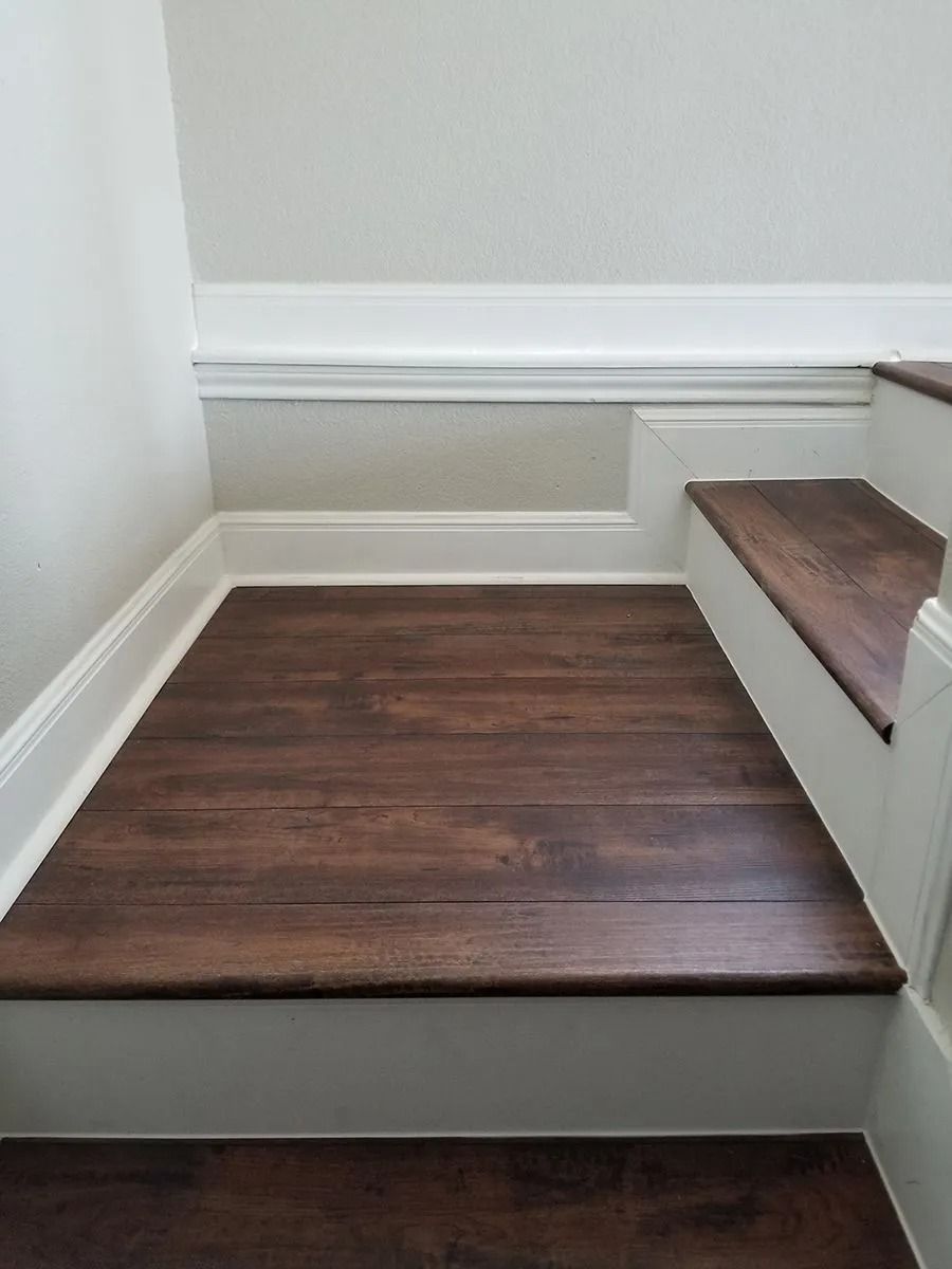 Small staircase with dark wood steps and white trim in a narrow interior hallway