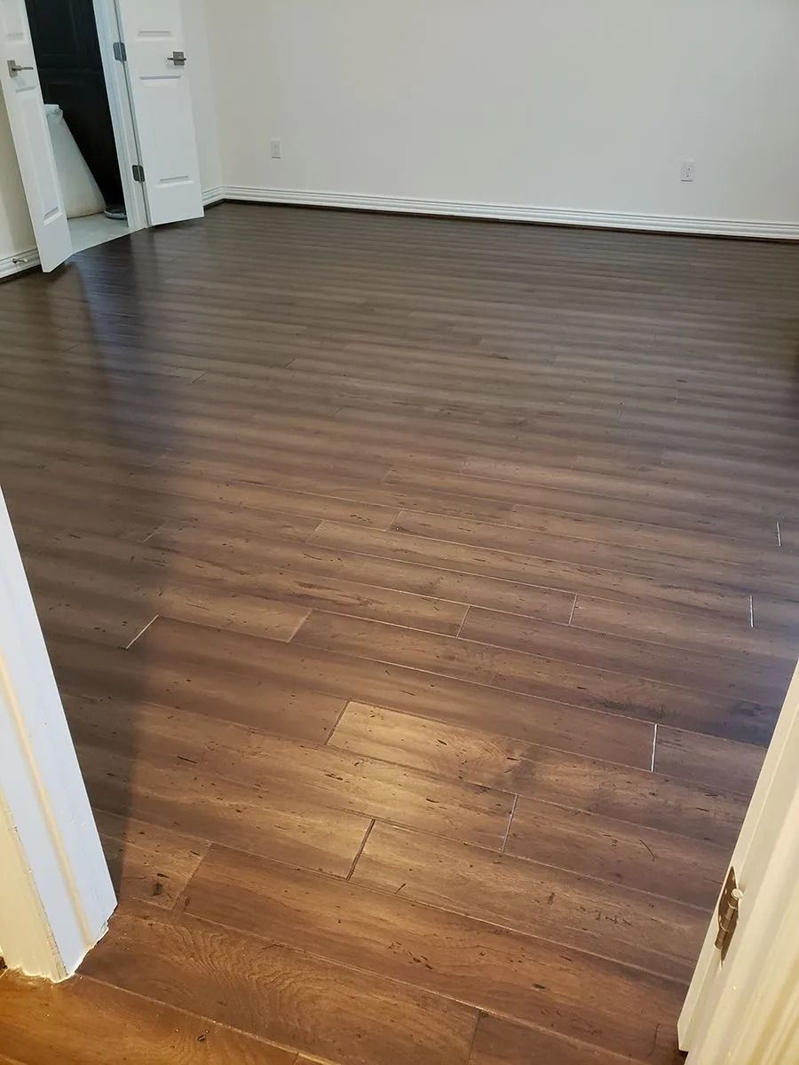 Empty room with dark wood flooring and white walls, viewed through a doorway