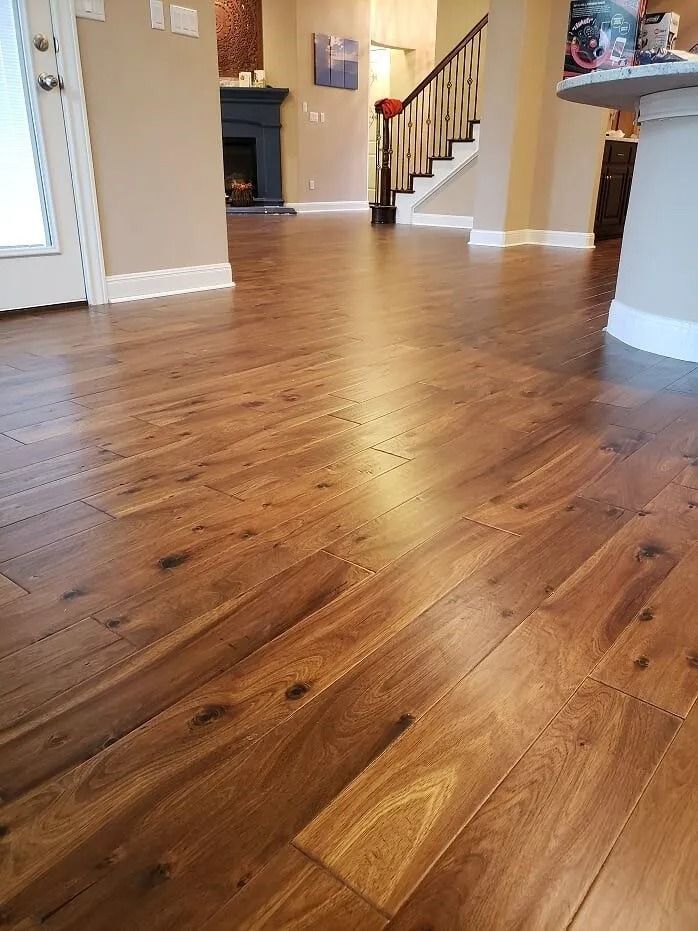 Empty hardwood-floored living room with staircase and fireplace in the background