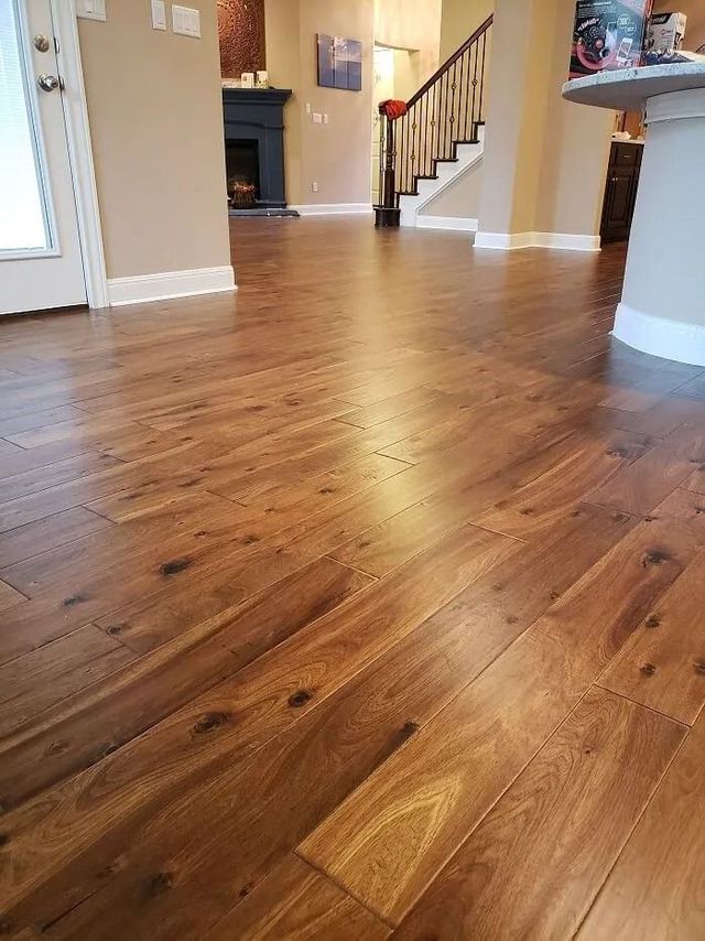 Polished wooden floor in a bright hallway with stairs and a fireplace in the background