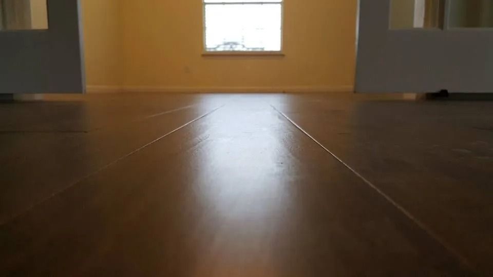 Low-angle view of a wooden floor leading to a bright window in an empty room