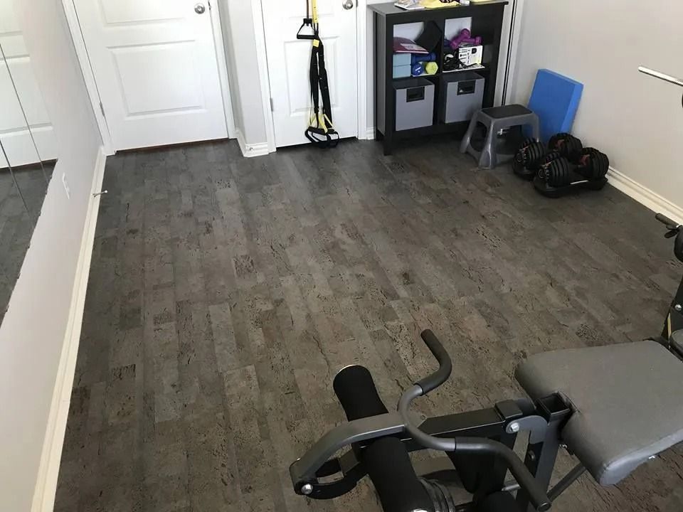 Small home workout room with exercise bike, shelving, dumbbells, and a doorway.