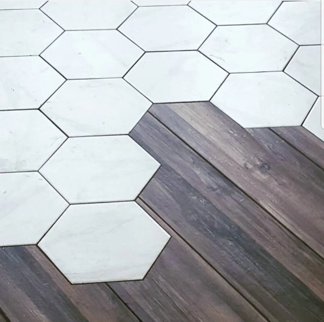 White hexagonal tile flooring transitions into dark wood planks along a diagonal seam.