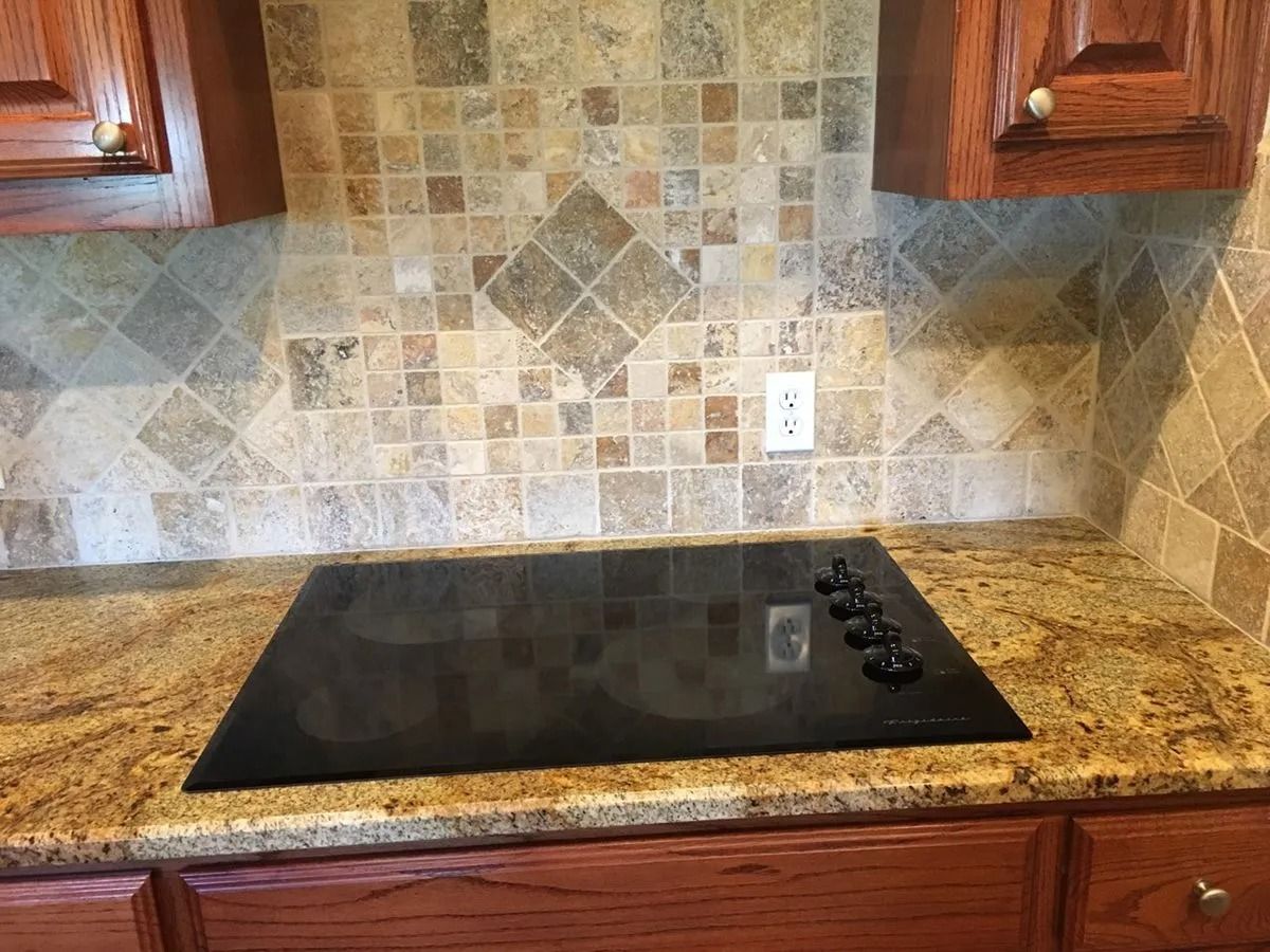 Kitchen countertop with black glass cooktop, granite counter, and tiled backsplash