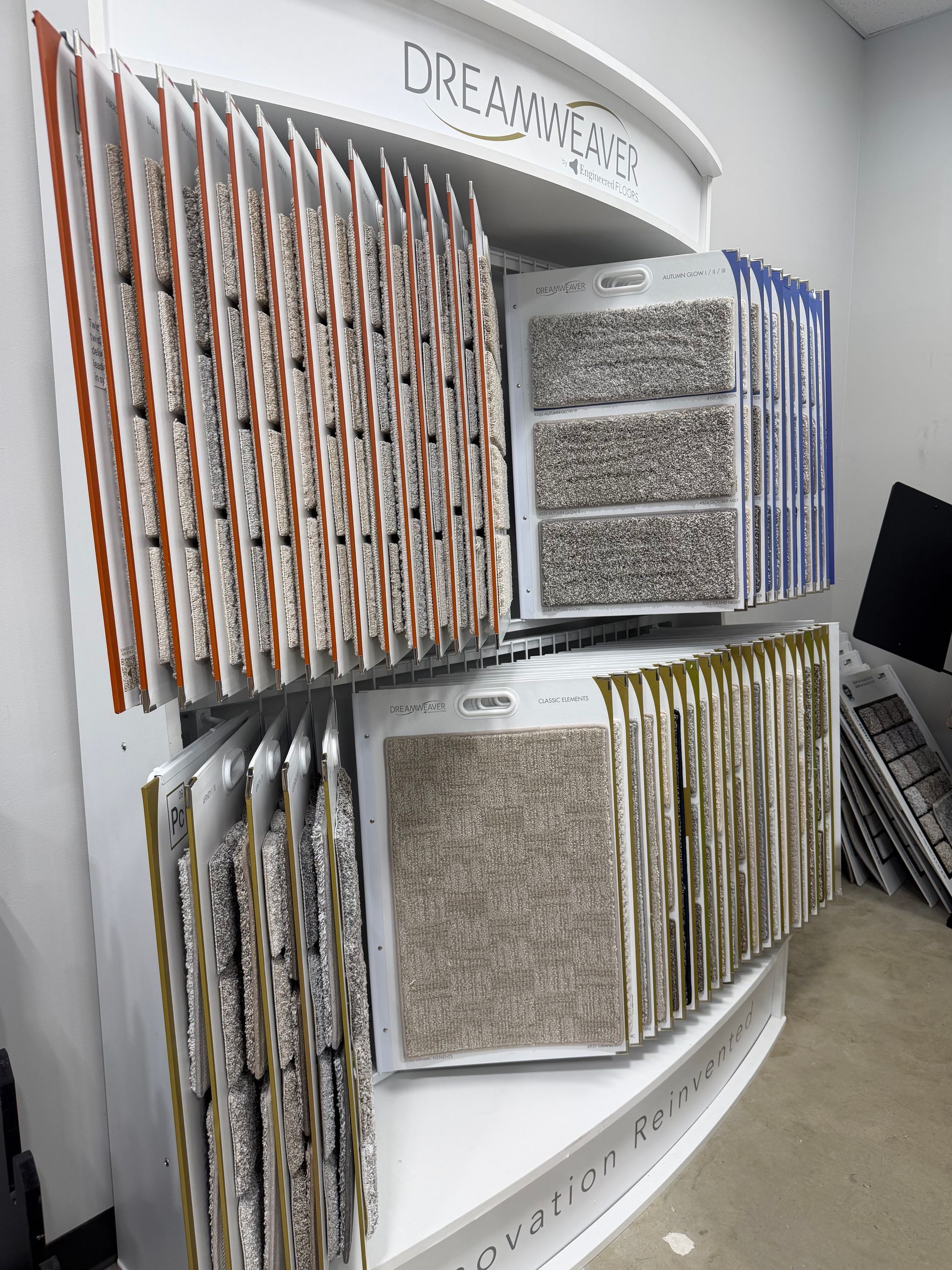 Wall display of stacked fabric or tile samples in gray, beige, brown, and blue in a showroom