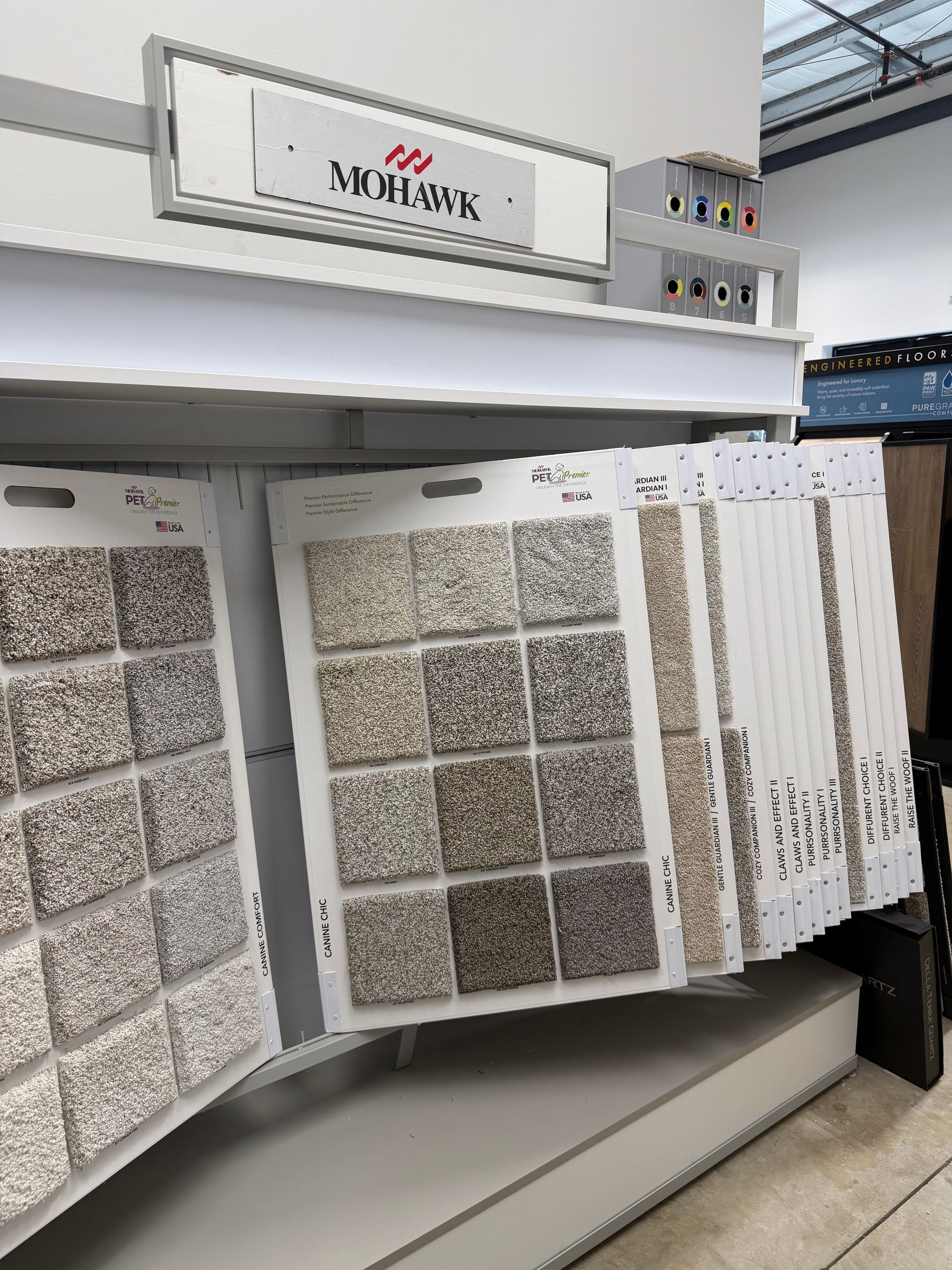 Tile samples displayed on a showroom rack under a lighted sign.