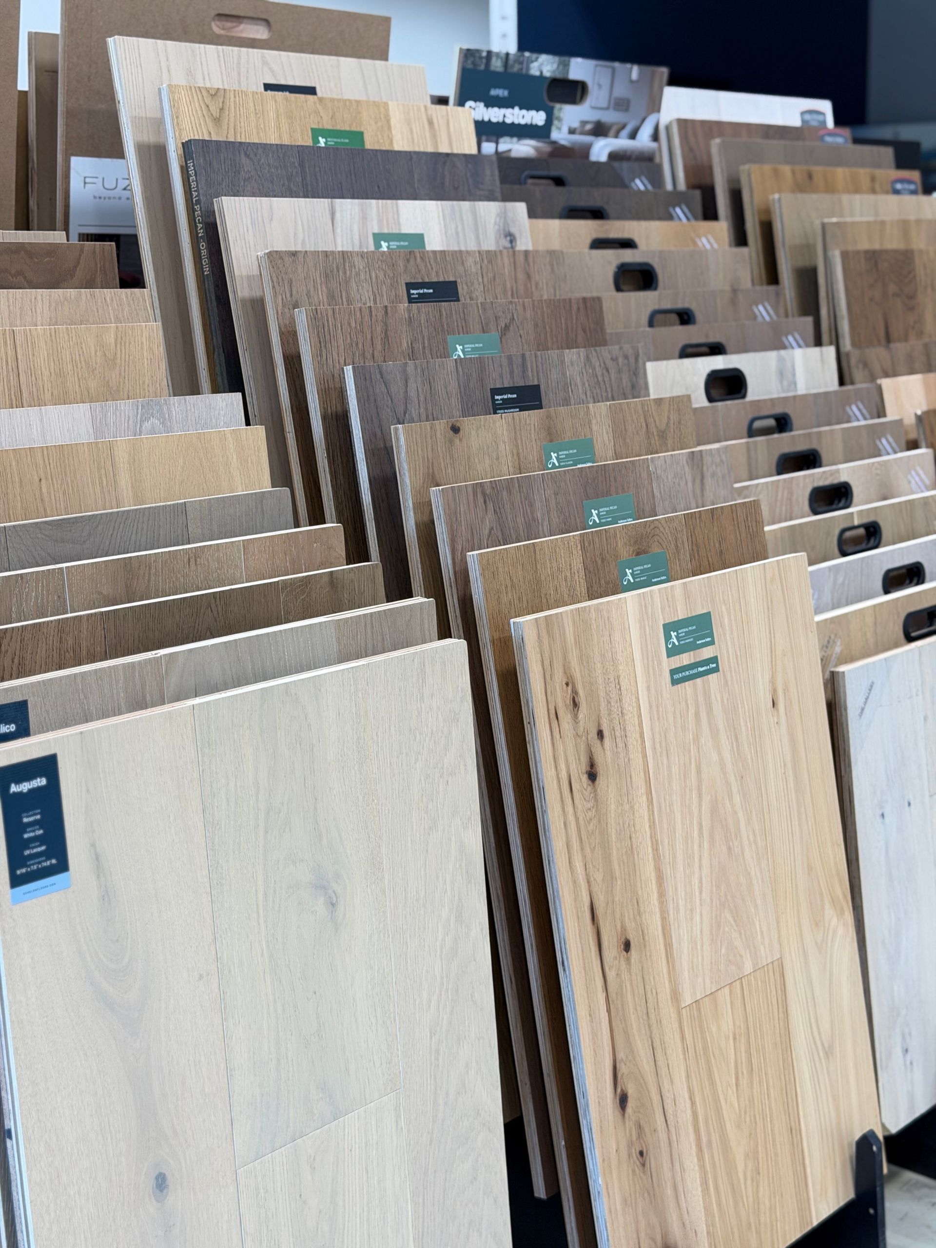 Assorted wood flooring samples displayed in a store rack, showing different colors and textures