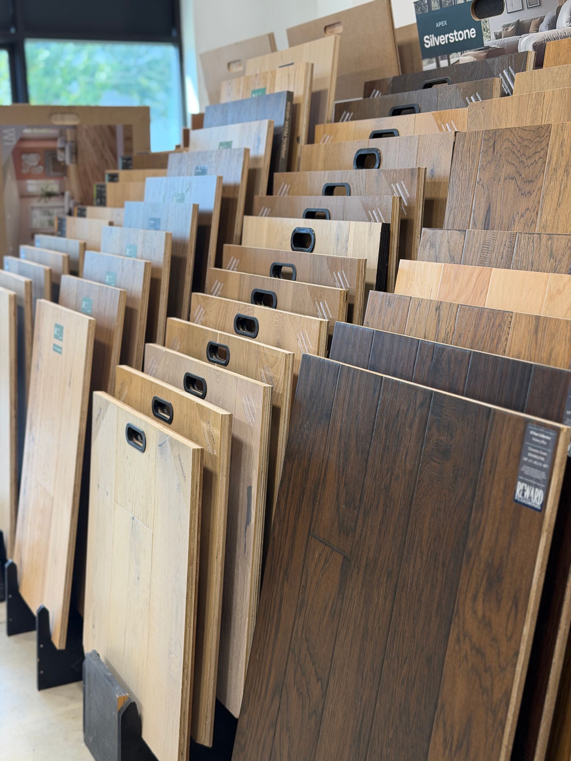 Wood flooring samples displayed upright in a showroom, showing various wood tones and finishes.