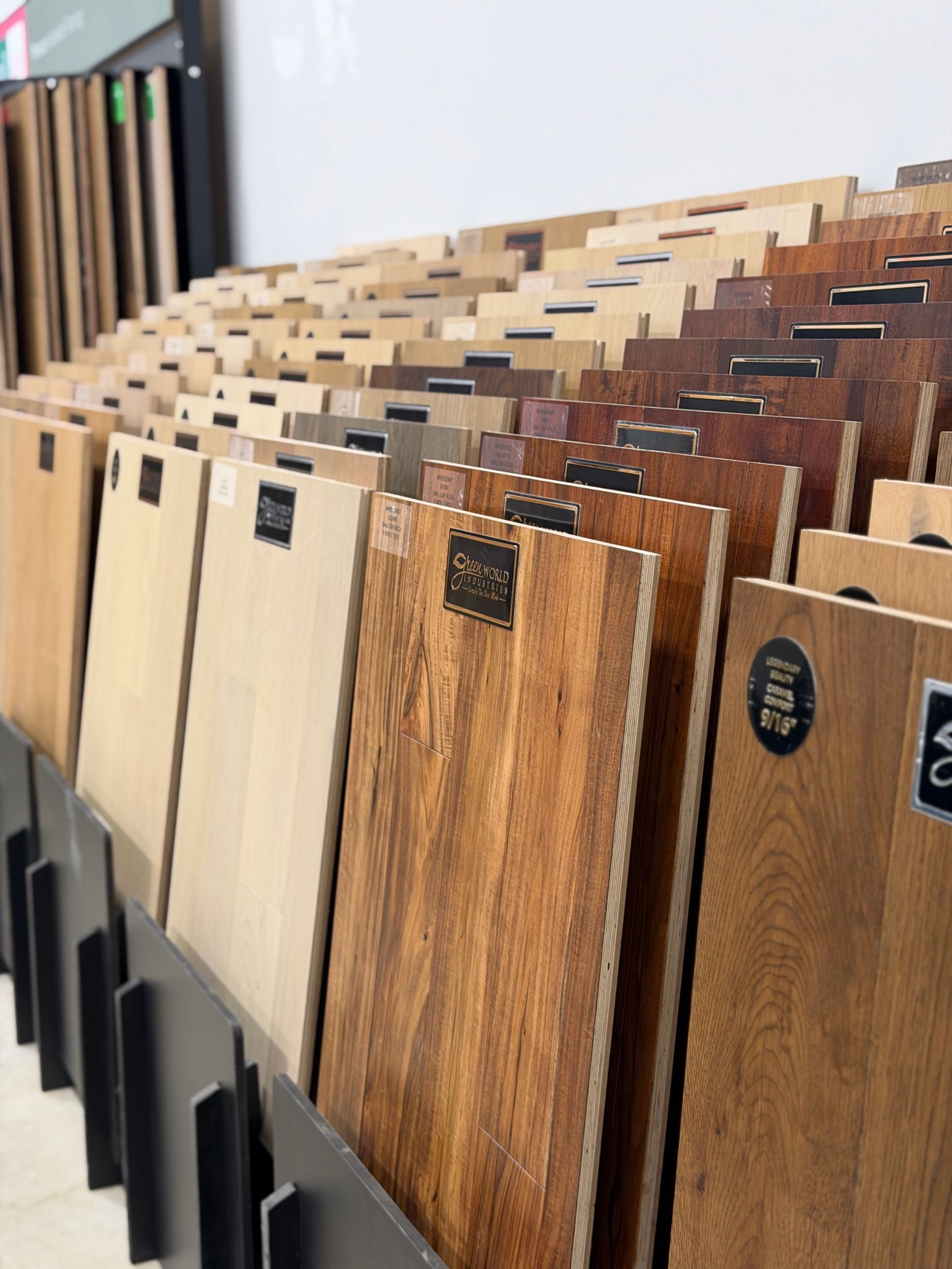 Rows of wood flooring samples in a showroom, showing various light and dark finishes.