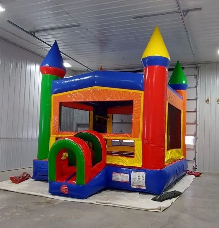 Colorful inflatable bounce house with castle towers in a large room.