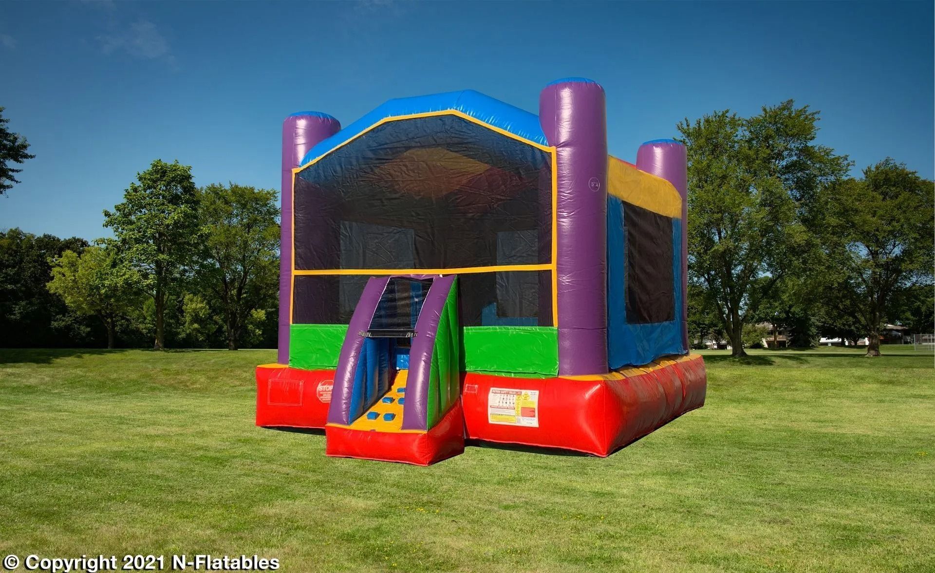Colorful inflatable bounce house on a grassy field under a blue sky.
