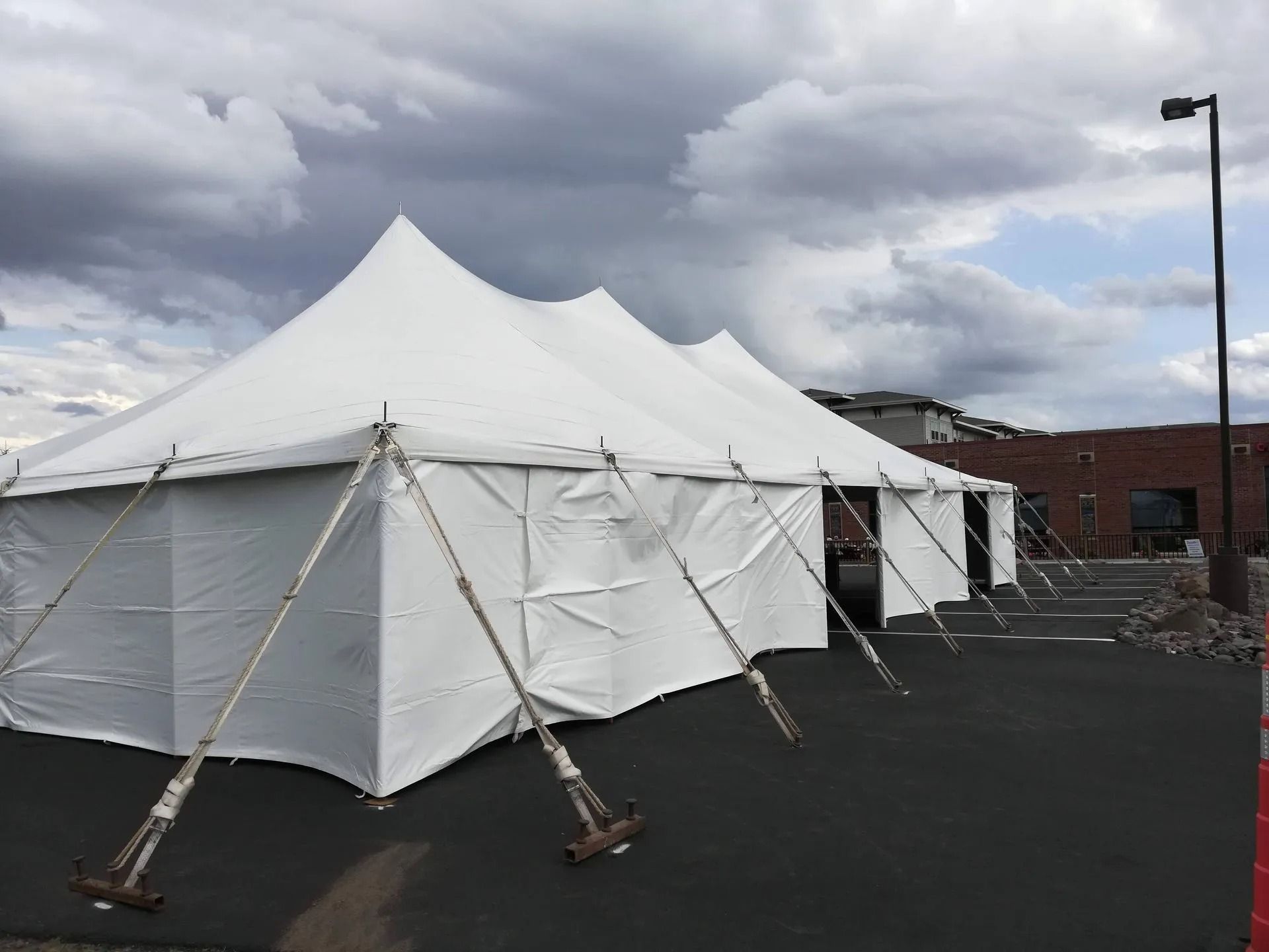 White party tent in parking lot, cloudy sky.