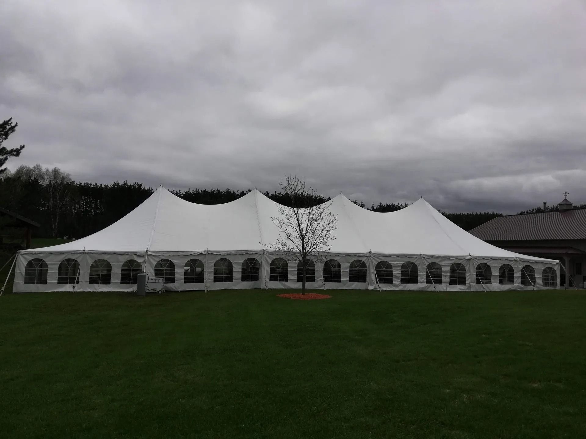 White tent on green grass under a cloudy sky.