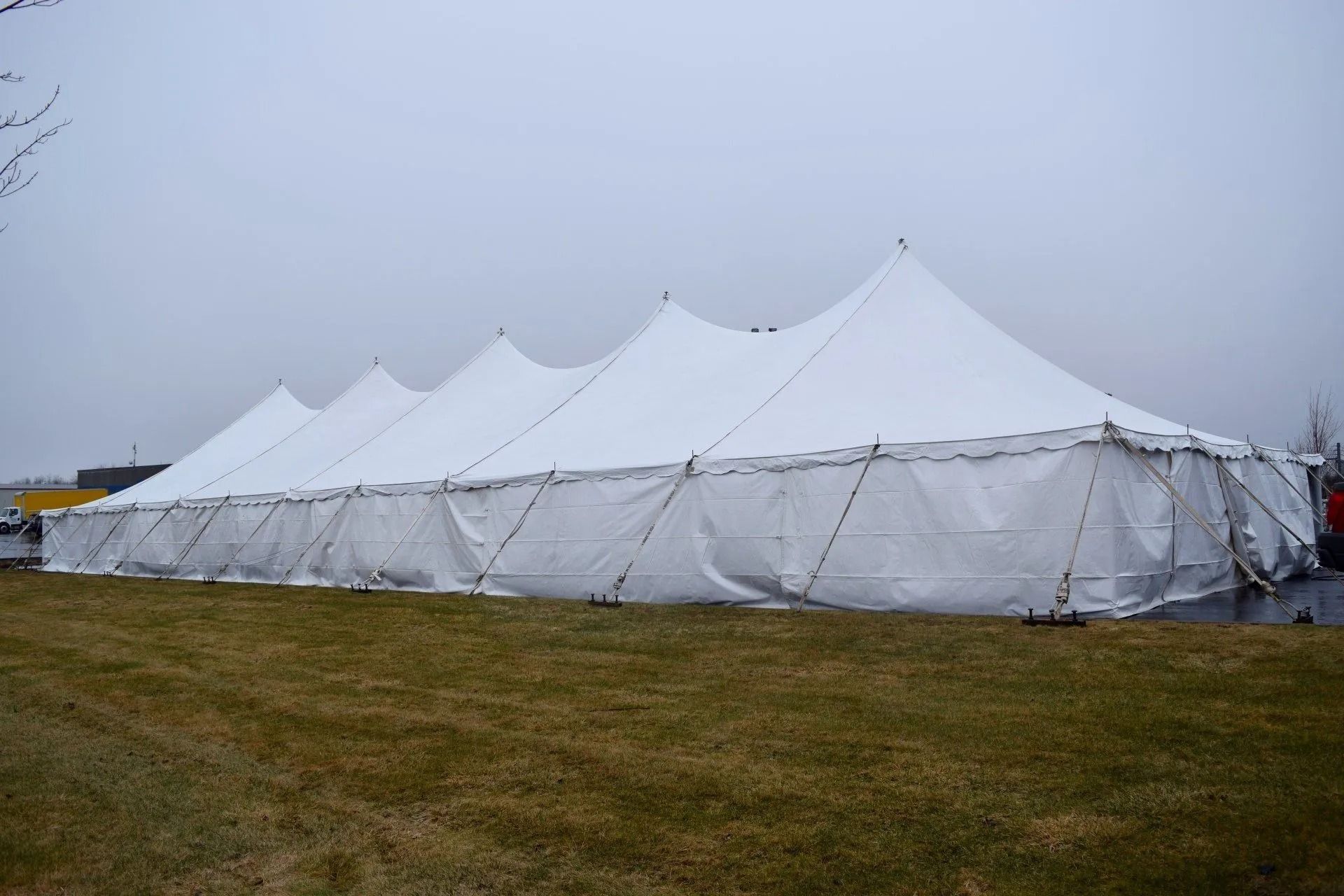 Large white tent set up on a grassy field, under a cloudy sky.