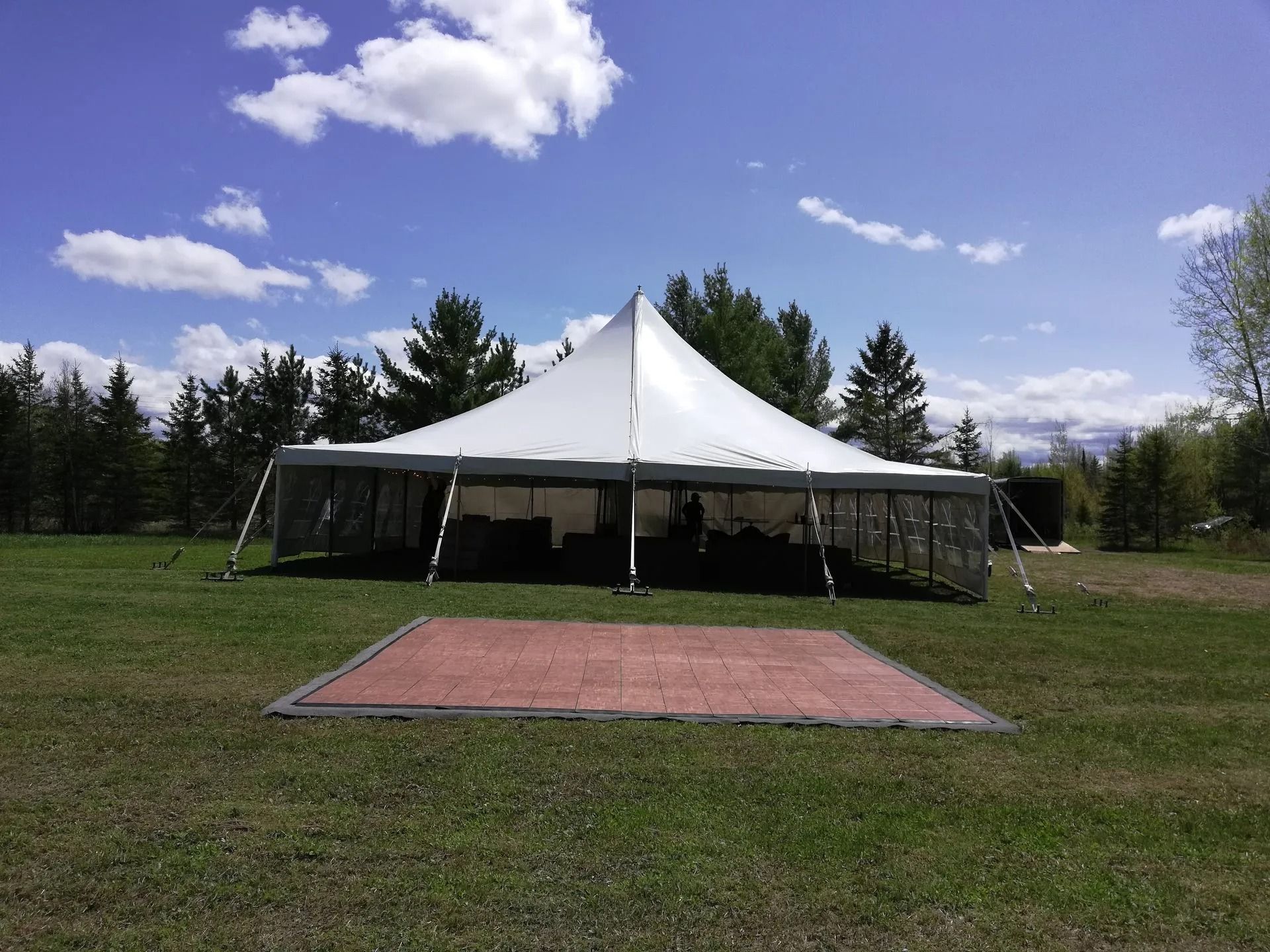 White event tent set up on green grass with a dance floor in front of it.