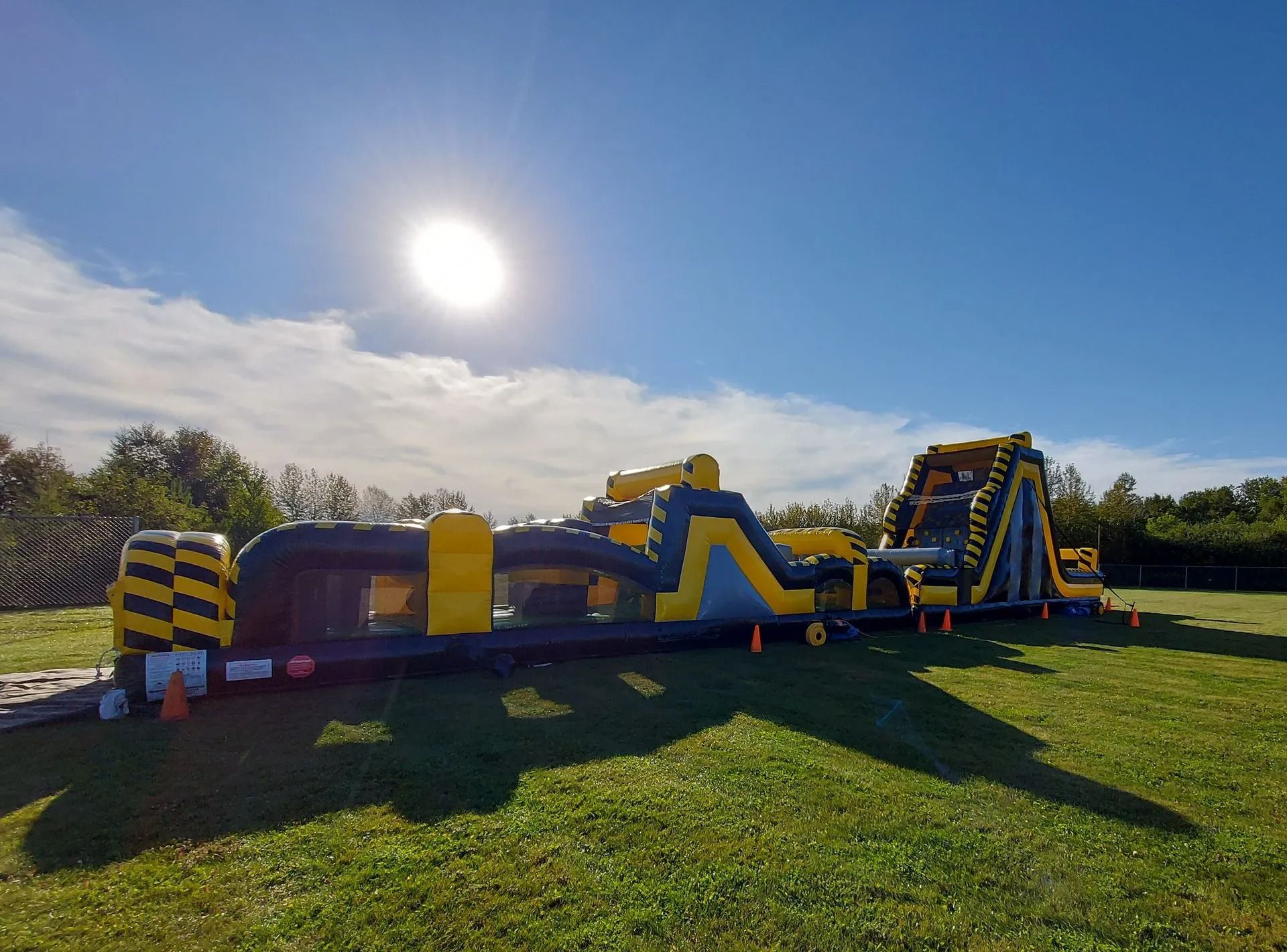 Large inflatable obstacle course on a grassy field under a bright blue sky.
