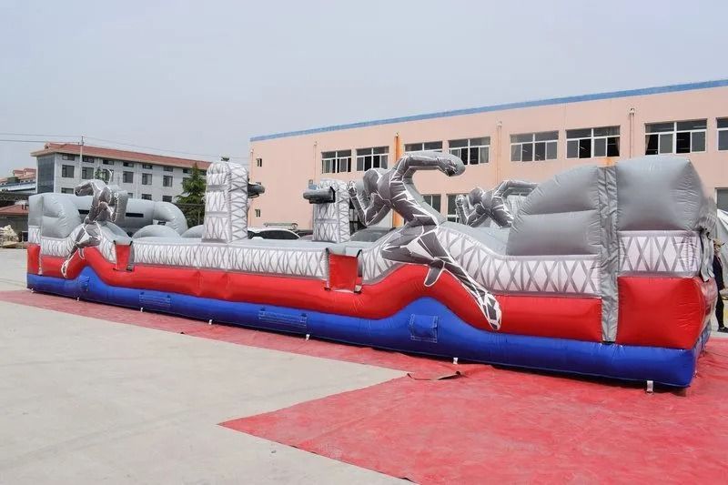 Inflatable obstacle course with red, blue, and gray sections, decorated with silhouetted figures.