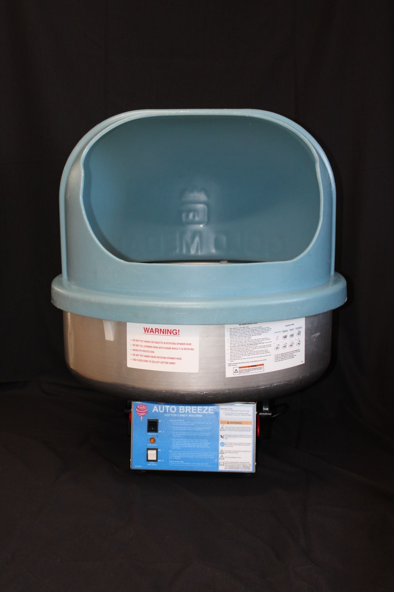 Blue and silver cotton candy machine with a control panel on a black background.