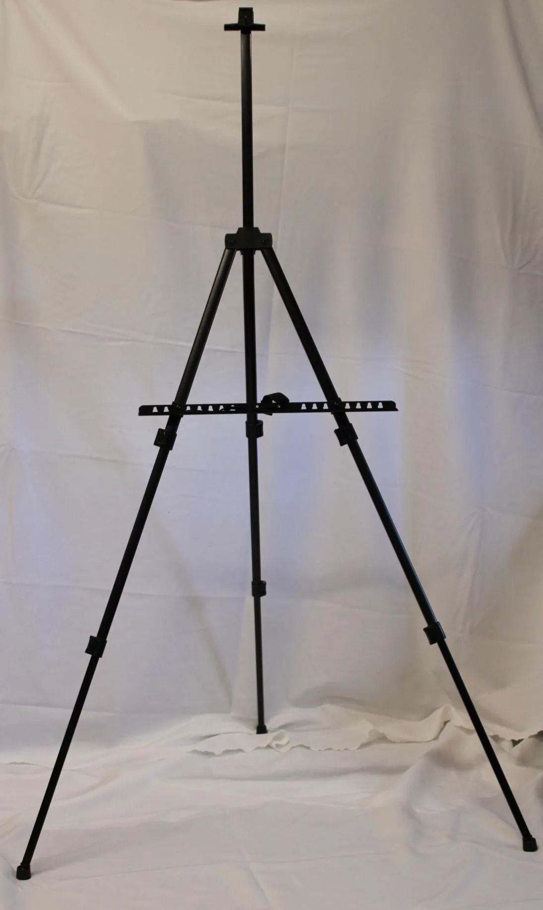 Black metal artist's easel on a white backdrop.