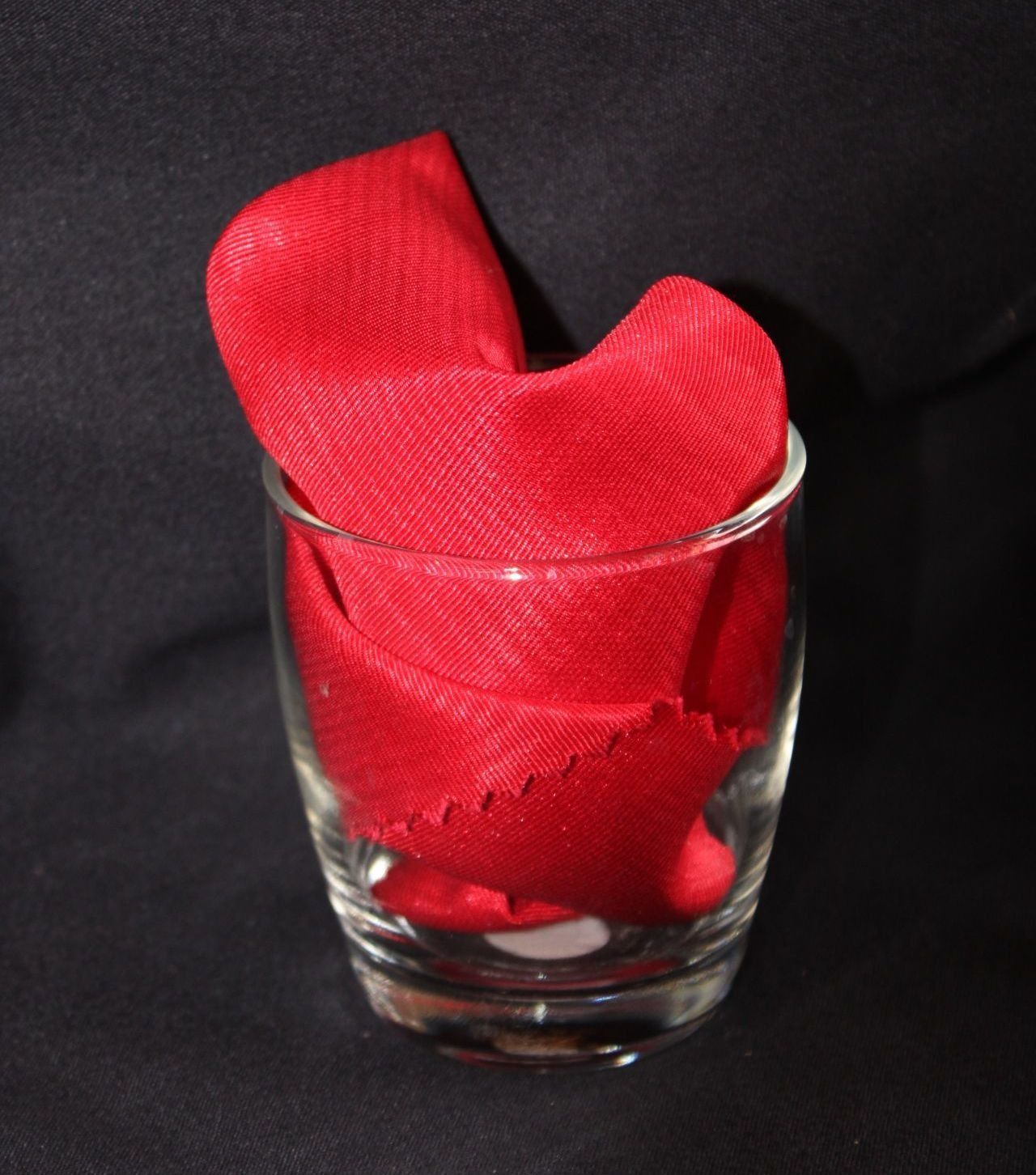 Red napkin folded in a clear glass.