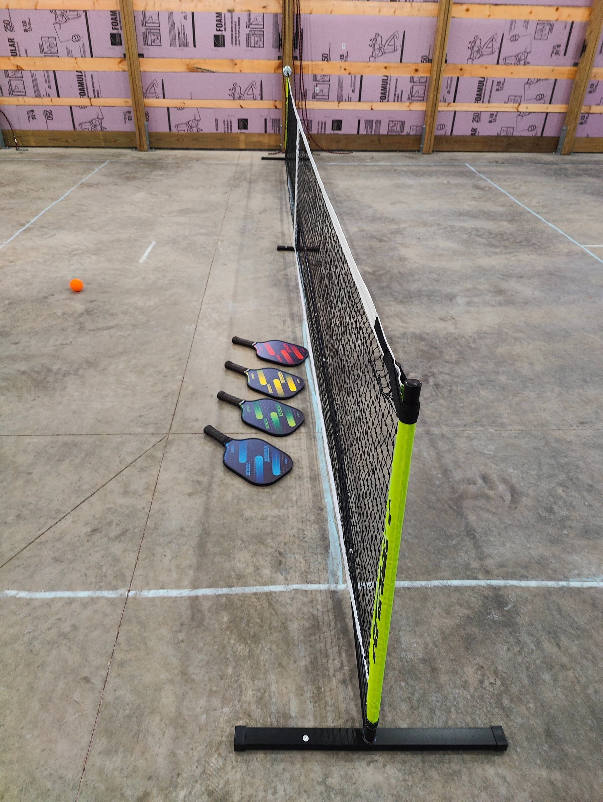 Pickleball setup with net, paddles, and ball on a court.