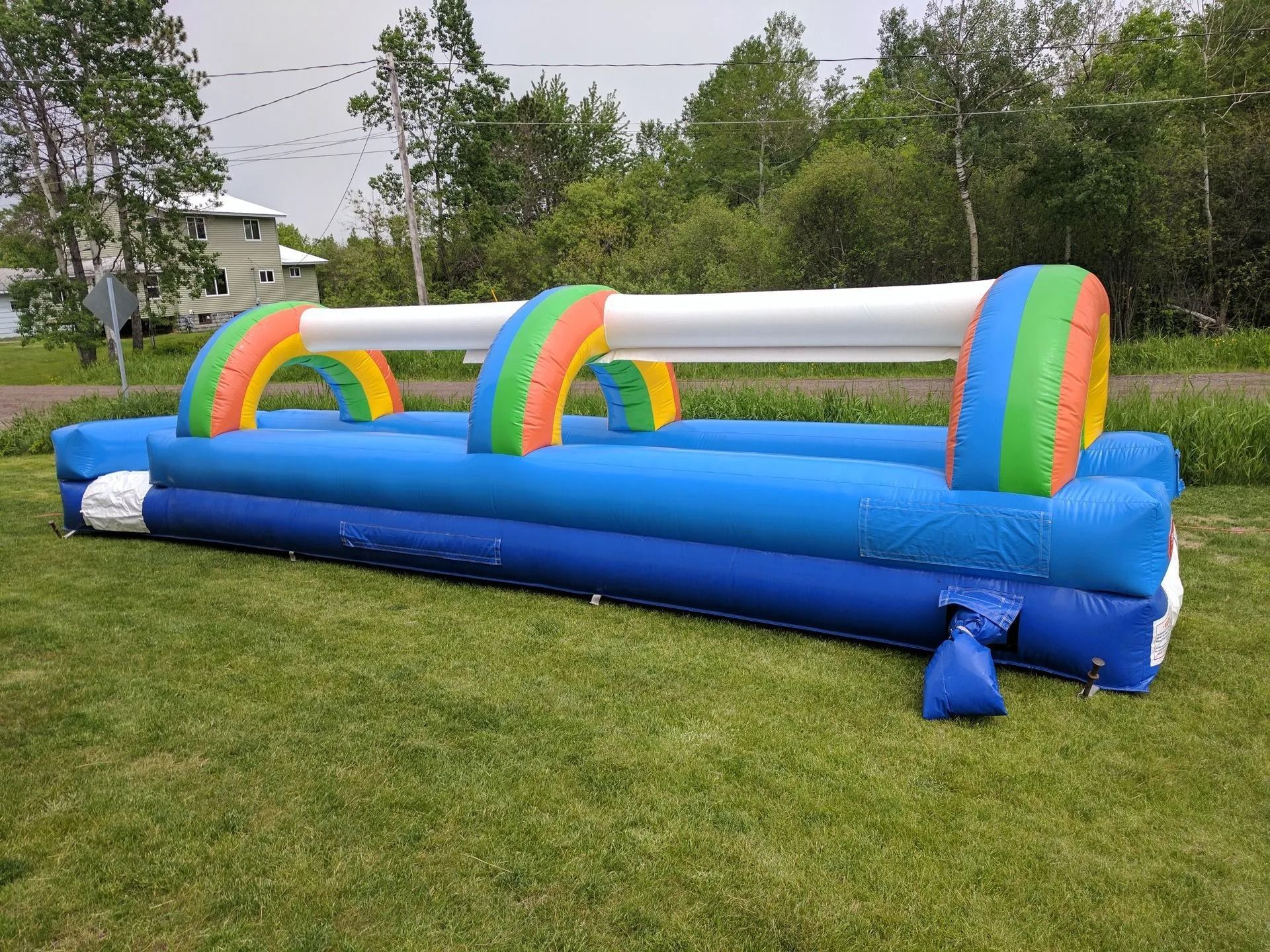 Inflatable blue and white obstacle course on grass, with colorful arches.
