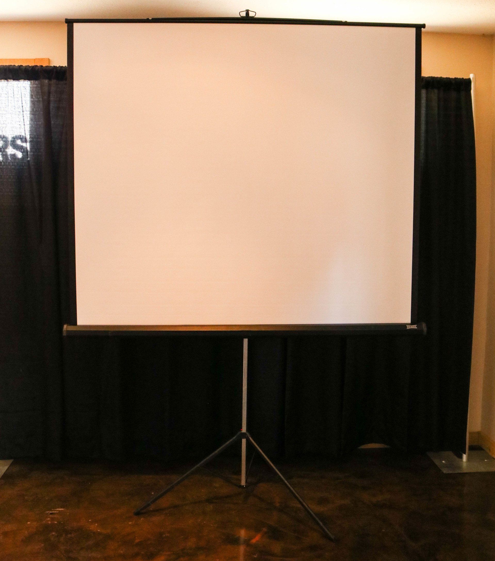 Projection screen on tripod stand in front of black curtains.