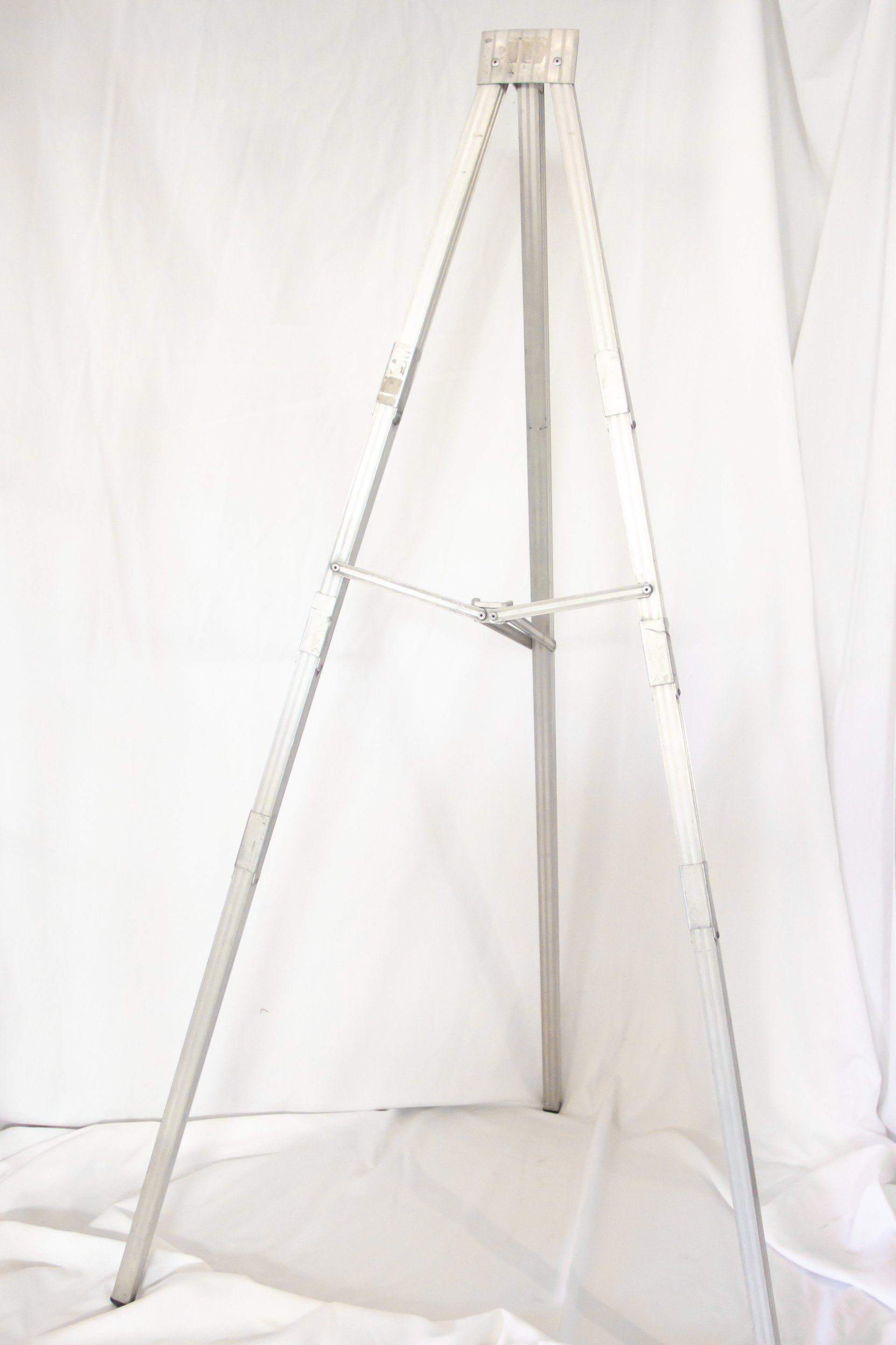 Silver metal artist easel on a white backdrop.
