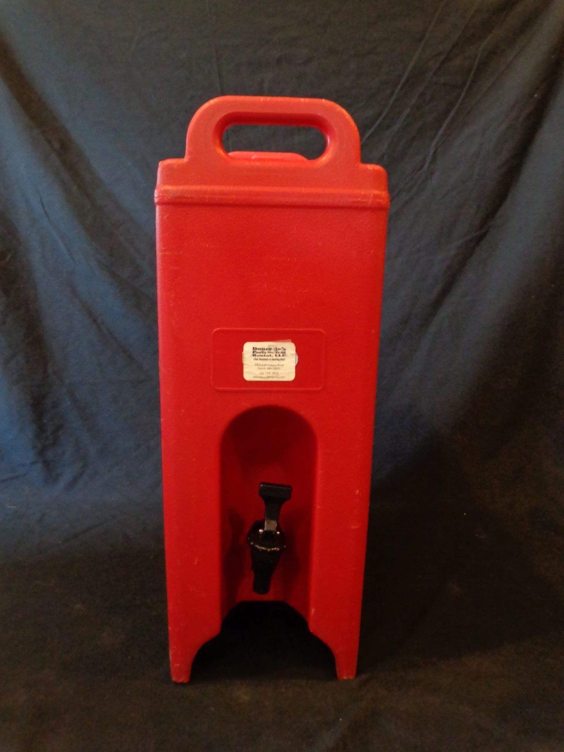 Red beverage dispenser with a black spigot and handle.