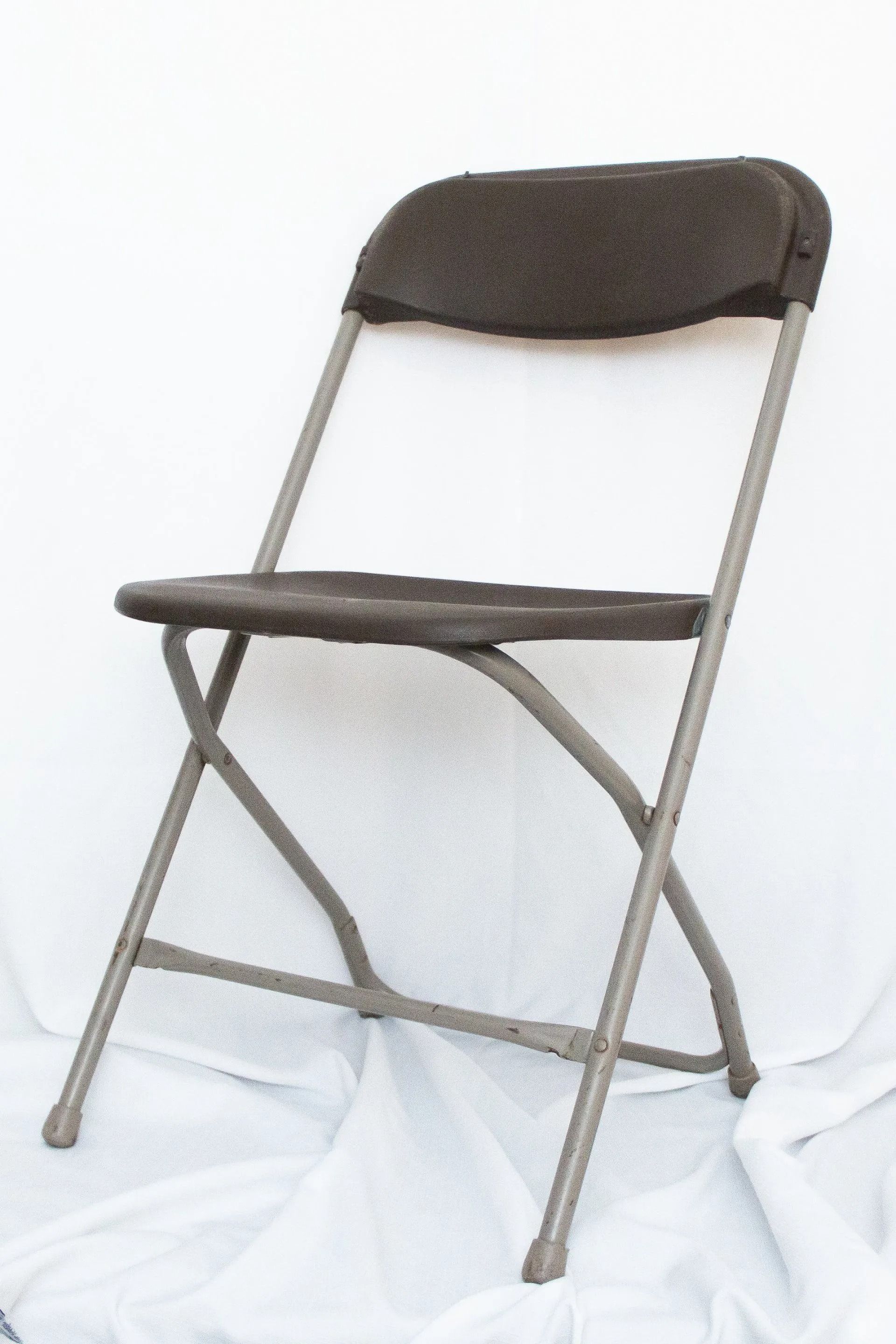 Folding chair, dark gray plastic seat and back, gray metal frame, on white fabric.