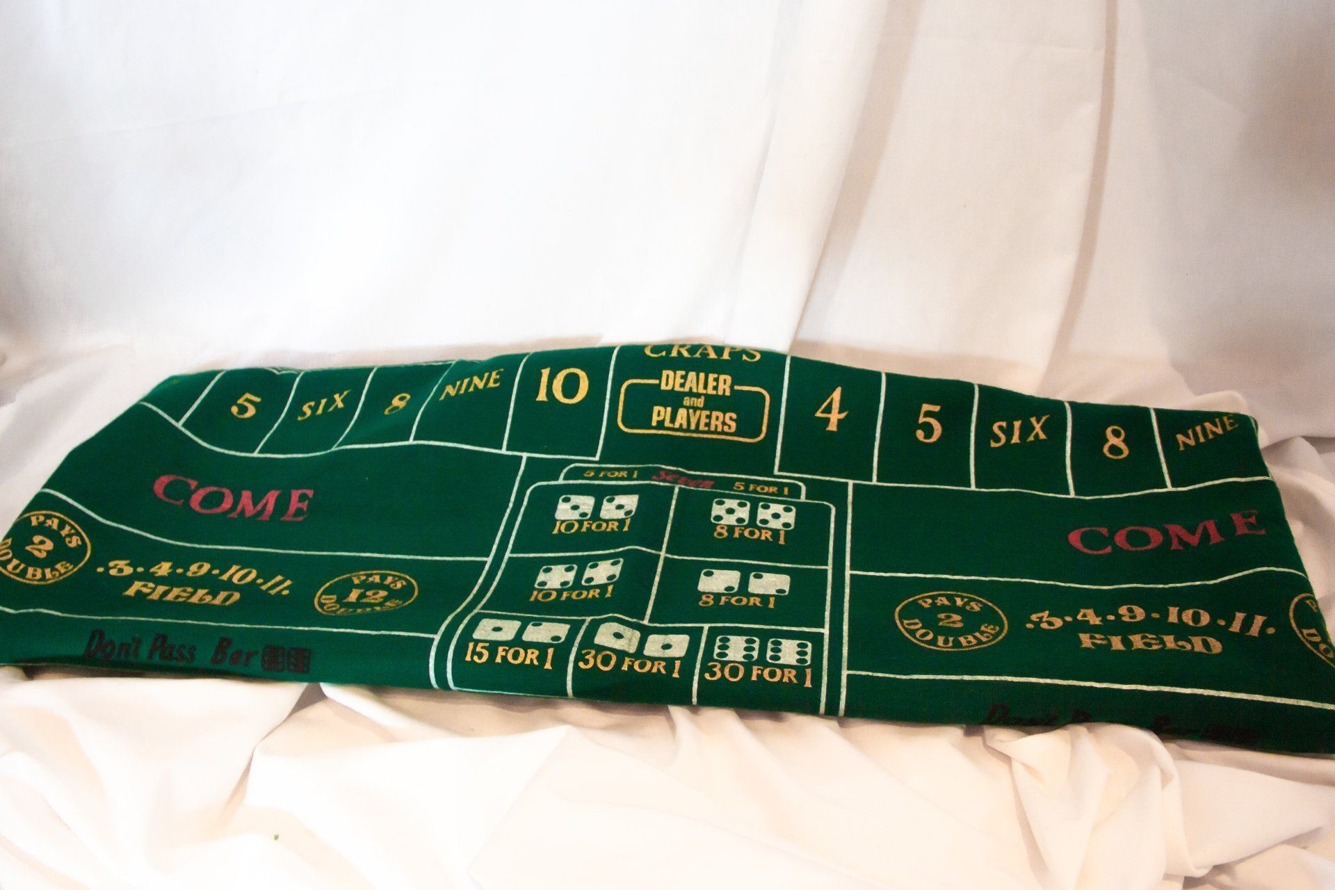 Green craps table on a white surface with text and betting areas.