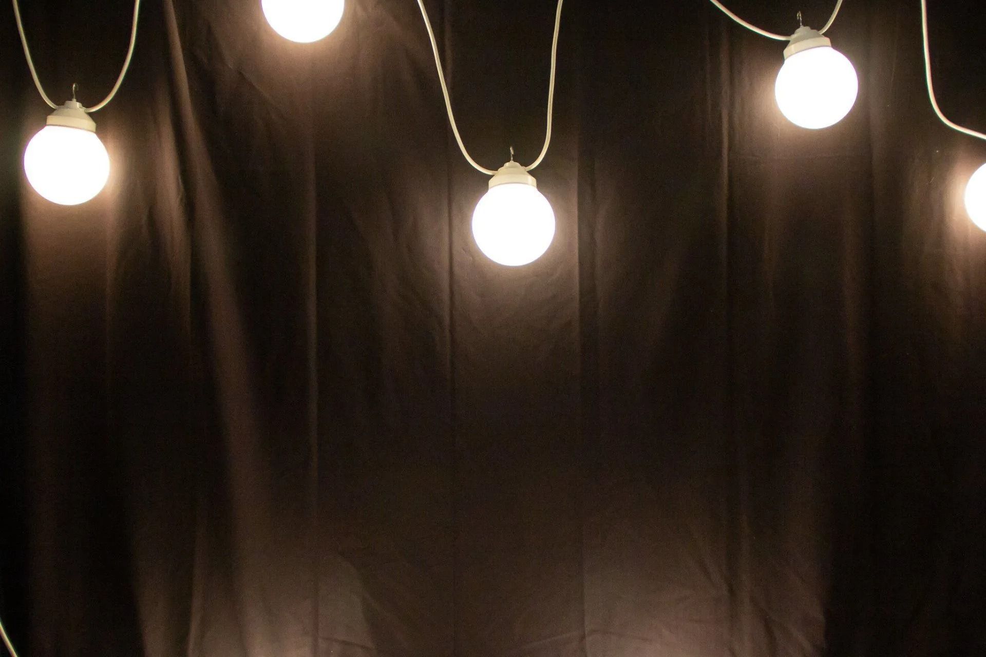 String of glowing white globe lights against a dark, textured backdrop.
