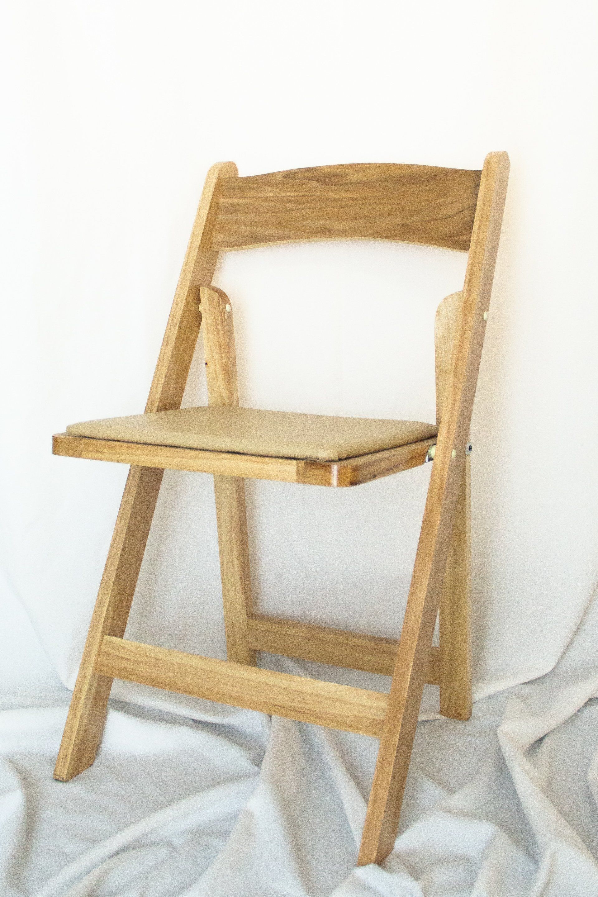 Wooden folding chair, beige cushion, against a white backdrop.