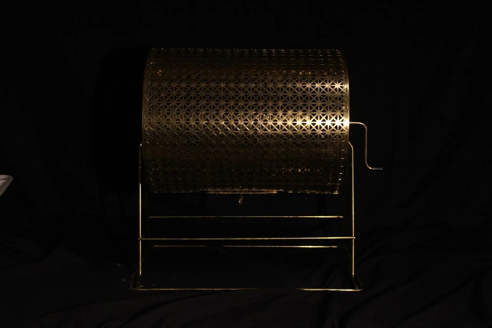 Gold-colored raffle drum on a stand, against a dark background.