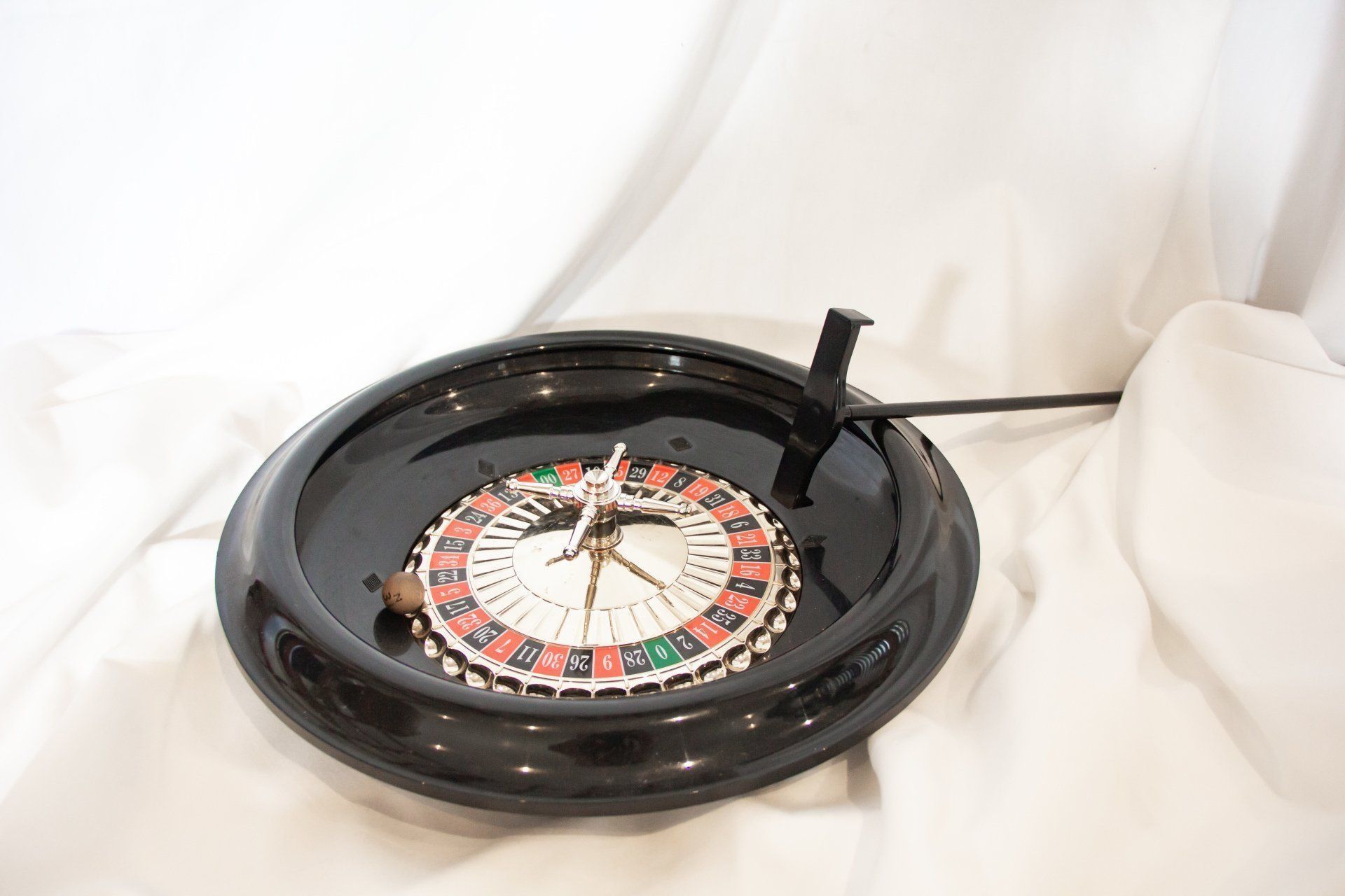 Black roulette wheel with a ball, on a white background.
